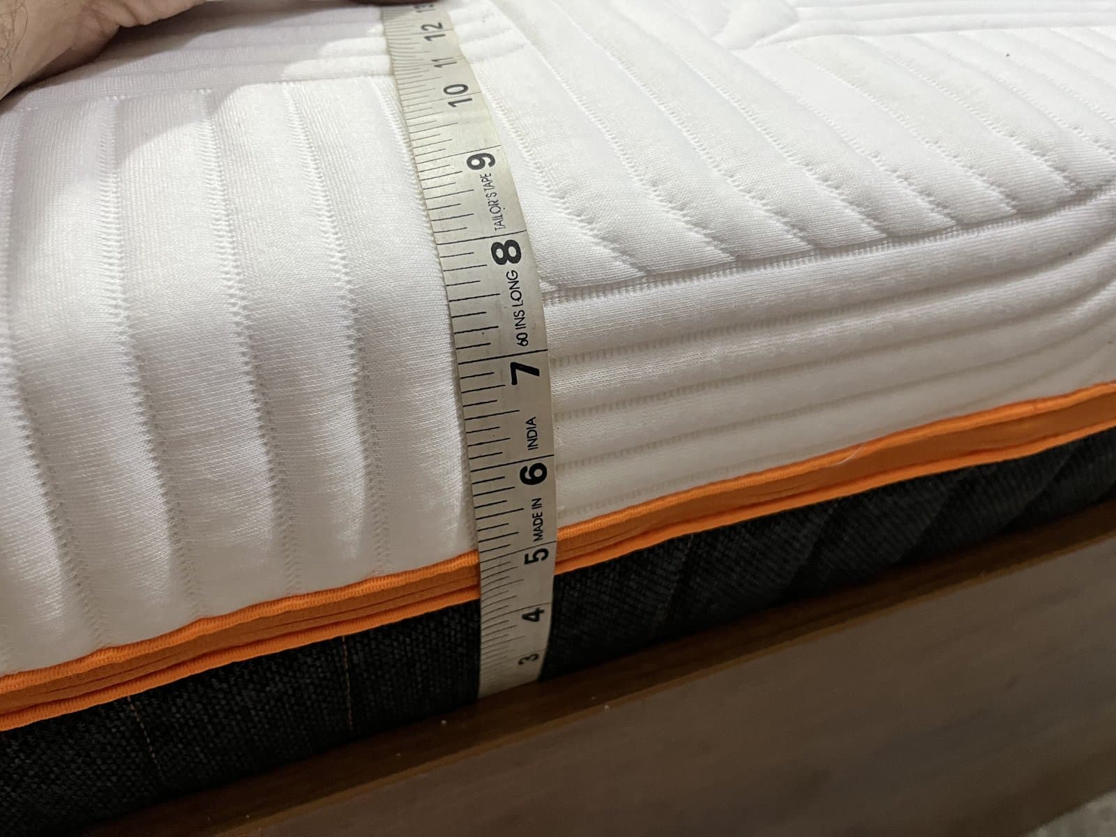 A tailor's tape running down the side of the mattress, showing about 8 inches of height.